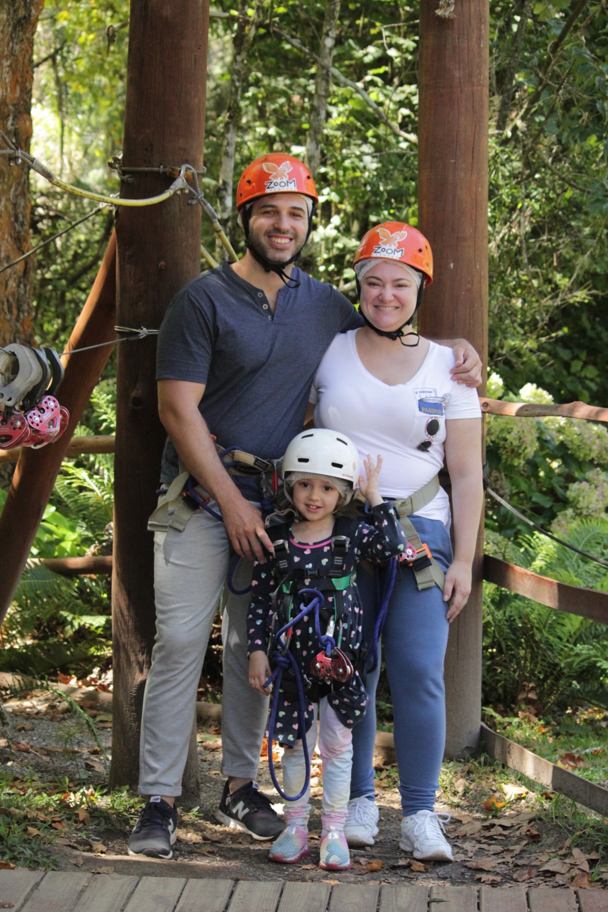 Família equipada para tirolesa em meio à floresta